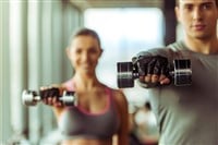 Attractive young muscular people working out with dumbbells in gym; Celsius stock 
